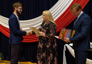 Pani dyrektor wraz z panem wicedyrektorem wręcza nagrodę Michałowi