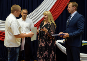 Pani dyrektor wraz z panem wicedyrektorem i wychowawcą wręcza nagrodę Błażejowi