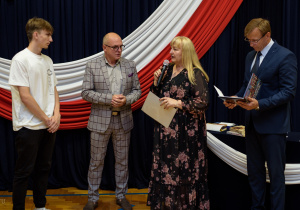 Pani dyrektor wraz z panem wicedyrektorem i wychowawcą wręcza nagrodę Kristianowi