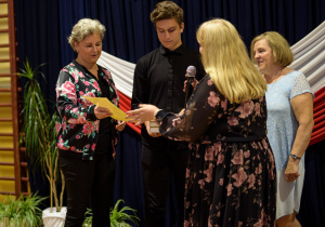 Pani dyrektor wraz z panem wicedyrektorem i wychowawcą wręcza list gratulacyjny mamie najlepszego ucznia w naszej szkole
