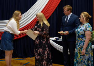 Pani dyrektor wraz z panem wicedyrektorem i wychowawcą wręcza nagrodę Izie