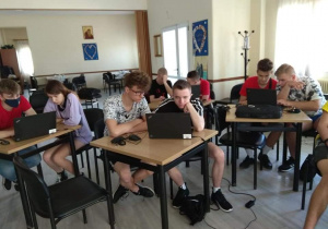 informatycy siedzący przy stolikach z laptopami