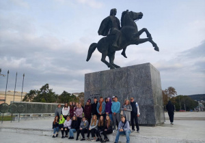 Grupa uczniów pod pomnikiem Aleksandra Macedońskiego pędzącego na koniu Bucefale