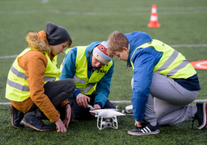Dwóch uczniów i instruktor podczas zajęć obsługi drona